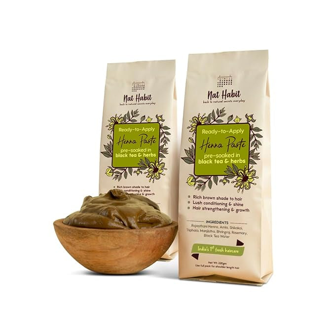 Two packages of Nat Habit Henna Paste with a wooden bowl containing the paste on a white background.