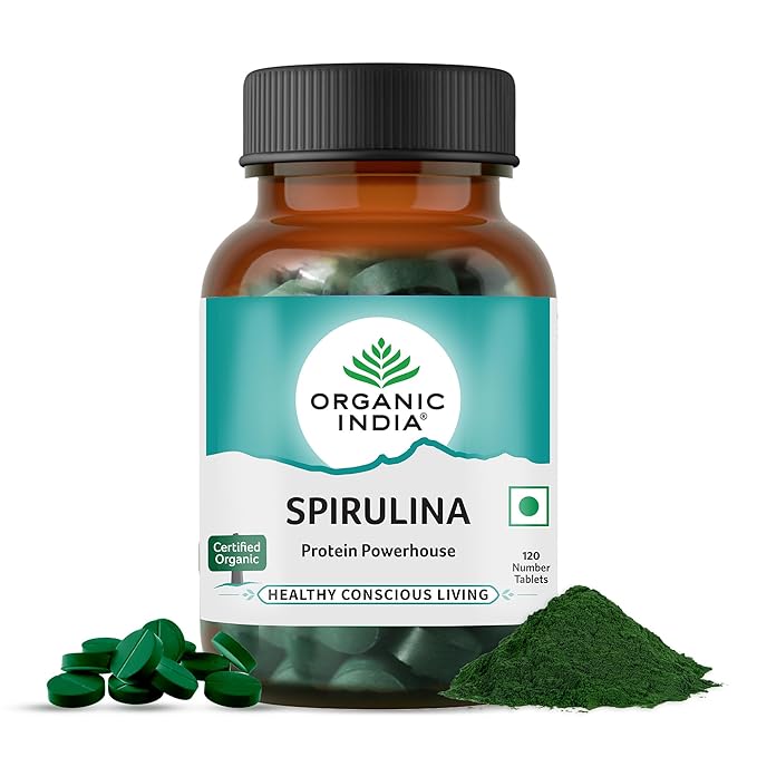 Bottle of Organic India Spirulina tablets with spirulina powder on a white background